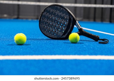 Black professional paddle tennis racket and ball with natural lighting on blue background. Horizontal sport theme poster, greeting cards, headers, website and app - Powered by Shutterstock