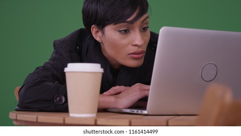 Black Professional Using Laptop Computer At Modern Cafe On Green Screen