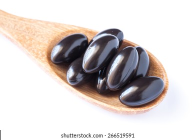 Black propolis capsules isolated on white, bee's product
