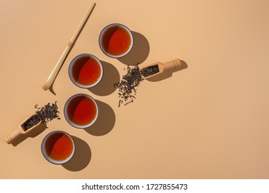 Black puer tea in ceramics bowls,dry pu-erh tea leaves in a wooden bamboo spoons on a beige background,tea ceremony minimalism