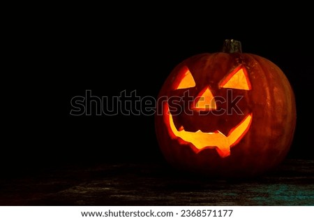 Black pumpkin with orange eyes. Halloween pumpkin on black background with horror theme.