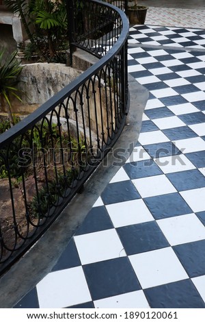 Black rail with checkerboard floor at hotel.