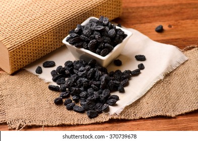 black raisins on a brown wooden table and a white canvas, close-up - Powered by Shutterstock