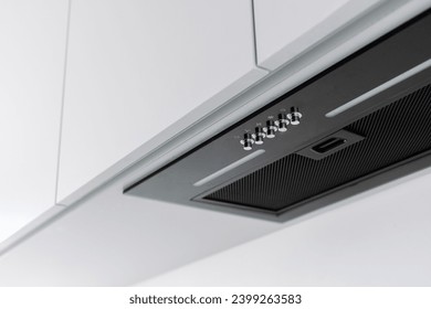 Black range hood with clean and new removable filter install inside white cupboard. Household appliances at modern kitchen with minimalist design. Professional domestic equipment for cooking at home