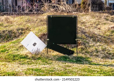 Black Realtor's Sign With Hanging Name Sign Partly Broken Off And Lot Number 6 Sign In Rough Grassy Vacant Lot For Sale - Selective Focus