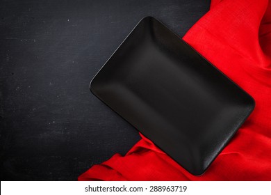 Black Rectangle Plate With Red Napkin On Black Wooden Table. Table Laying. Top View.