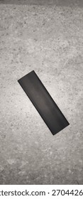 Black Rectangular Object on Gray Cement Floor
