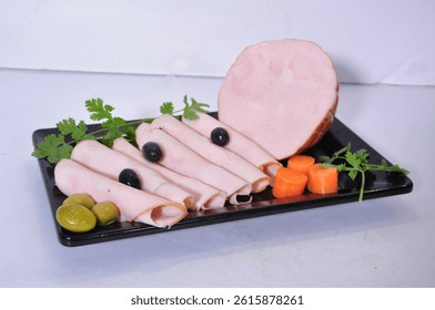 A black rectangular plate features slices and a block of light pink Al Wadi Smoked Turkey, garnished with green parsley, black olives, and vibrant orange carrot pieces.