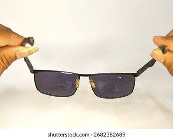 Black rectangular sunglasses held by hands isolated on white background.