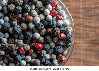 Black, red and white peppercorns in bowl on a wooden background. Mix of different peppers. Top view, close up - Powered by Shutterstock