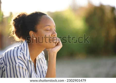 Black relaxed woman resting alone in a park at sunset