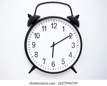 Black Retro Alarm Clock Showing 06:10 or 18:10. Classic Bell Style on White Wood Background.