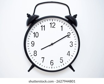 Black Retro Alarm Clock Showing 08:10 or 20:10. Classic Bell Style on White Wood Background.
