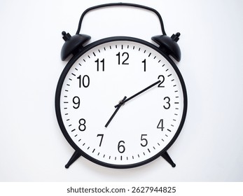 Black Retro Alarm Clock Showing 07:10 or 19:10. Classic Bell Style on White Wood Background.