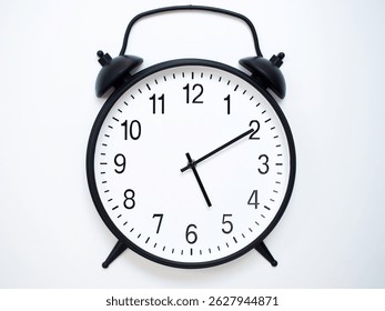 Black Retro Alarm Clock Showing 05:10 or 17:10. Classic Bell Style on White Wood Background.