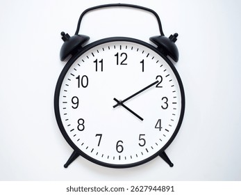 Black Retro Alarm Clock Showing 04:10 or 16:10. Classic Bell Style on White Wood Background.
