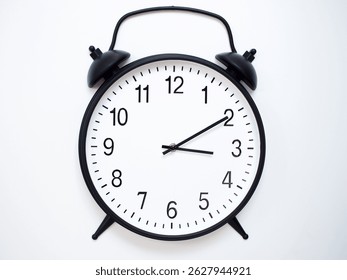 Black Retro Alarm Clock Showing 03:10 or 15:10. Classic Bell Style on White Wood Background.
