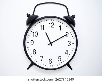 Black Retro Alarm Clock Showing 11:10 or 23:10. Classic Bell Style on White Wood Background.