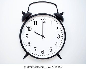 Black Retro Alarm Clock Showing 10:00 or 22:00. Classic Bell Style on White Wood Background.