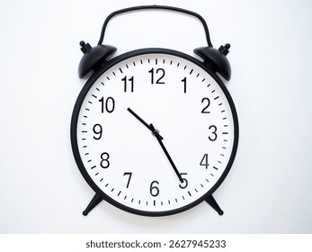 Black Retro Alarm Clock Showing 10:25 or 22:25. Classic Bell Style on White Wood Background.
