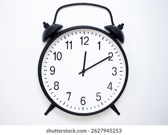 Black Retro Alarm Clock Showing 00:10 or 12:10. Classic Bell Style on White Wood Background.