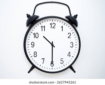 Black Retro Alarm Clock Showing 10:30 or 22:30. Classic Bell Style on White Wood Background.