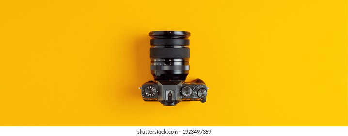Black retro camera on yellow background. Photography concept with flat lay overhead wide view.