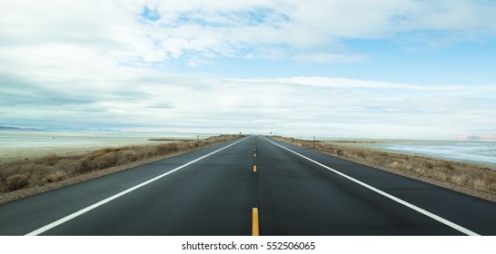 The black road heading straight ahead. Flanked by the sea - Shutterstock ID 552506065