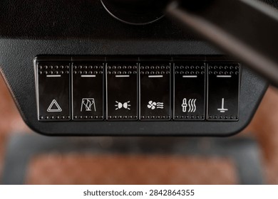 Black rocker switch panel with function symbols on vehicle dashboard in close-up view.