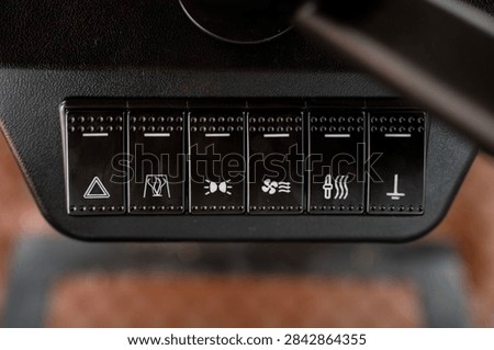 Black rocker switch panel with function symbols on vehicle dashboard in close-up view.