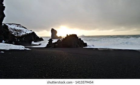 Black rocks at sea on black sand beach by Snaefellsnes Peninsula on Iceland's rugged North Western coast - Sunset over the beautifully violent ocean - Powered by Shutterstock