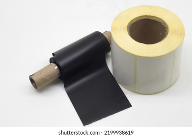 Black roll wax ribbon for thermal transfer on core and white self-adhesive label roller for a special barcode printer. Consumables and auxiliary materials for barcode printing. Selective focus - Shutterstock ID 2199938619