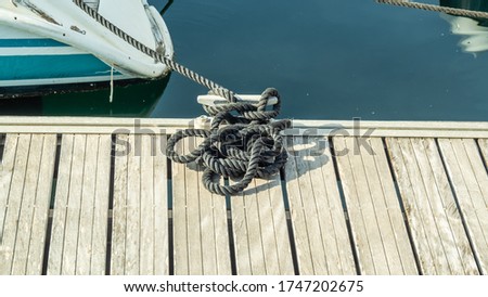 Black rope tied to the bollard and white Board berth