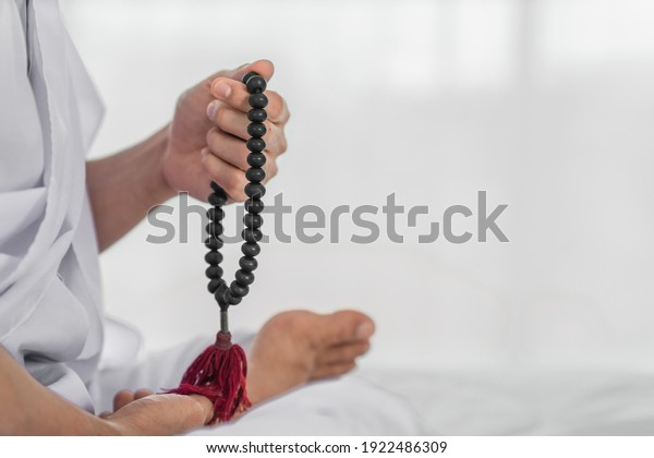 black rosary\
beads in hand of religious buddhist man in white clothing having\
sitting and rosary count\
meditation