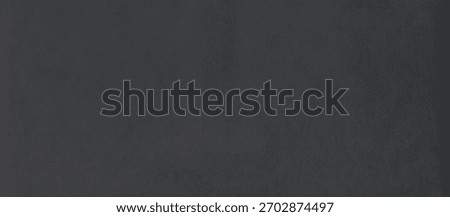 Black rough surface of old paper or cardboard, background, texture. Backdrop of black paper surface with elements of aging. Old and shabby paper piece. Ancient wall in ashen color. Black paper surface