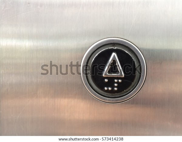 black rounded\
go up button at a lift steel\
panel