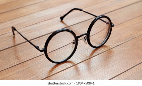 Black round-framed glasses on a wooden table