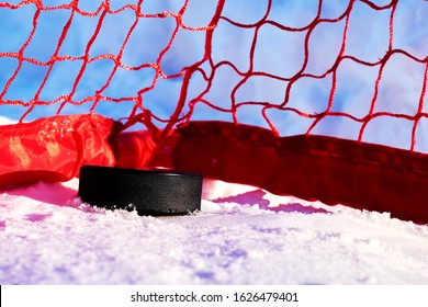 A Black Rubber Puck Lies In The Red Goal After A Goal Scored Near The Post. Ice Hockey World Championship. Winter Street Sports.