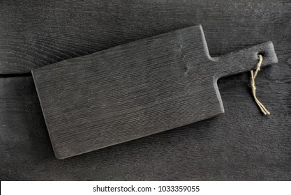 Black Rustic Cutting Board On Wooden Table, Top View