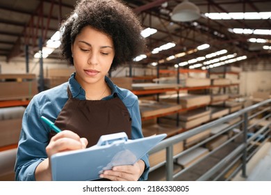 Black Saleswoman Taking Notes On Clipboard At Storehouse