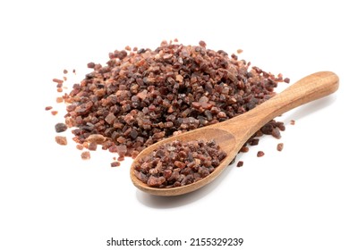 Black salt was placed in a wooden spoon and piled a lot on a completely white background.