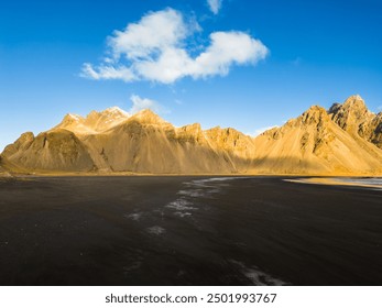 Black sand beach with huge rocky hills in amazing nordic surroundings, famous vestrahorn mountains and fields in Iceland. Stokksnes beach creating wintry landscape, arctic ocean shoreline. - Powered by Shutterstock