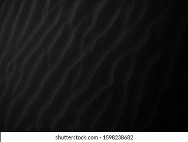 Black Sand beach macro photography. Texture of black volcanic sand for background. Close-up macro view of volcanic sand surface black color. Black and white poster texture sand in the desert. 