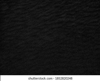 Black Sand beach macro photography. Texture of black volcanic sand for background. Close-up macro view of volcanic sand surface black color. Black and white poster texture sand in the desert.