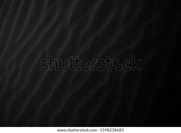 Black Sand beach macro photography. Texture of black\
volcanic sand for background. Close-up macro view of volcanic sand\
surface black color. Black and white poster texture sand in the\
desert. 