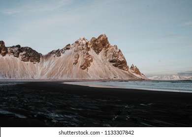 The black sand beach at Stokksnes, Iceland in front of some snow covered mountains at sunset. - Powered by Shutterstock