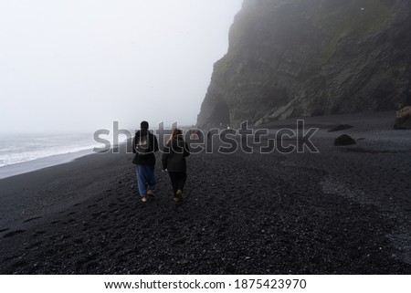 Black sand beach Vik Reynisfjara in Iceland with two tourists in the background