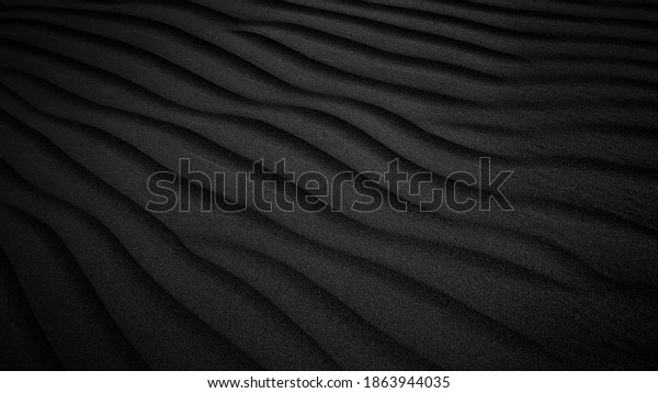 Black Sand dune. Black Sand beach\
macro photography. Background, texture, wave pattern of oceanic\
sand on the beach, black. Texture of beach sand. Black\
beach.
