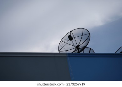 Black satellite TV receiver plate on the roof with a blue sky background.