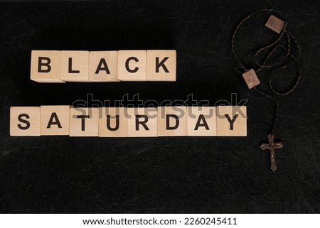 Black Saturday holy week concept. Wooden blocks typography with rosary flat lay in dark background.